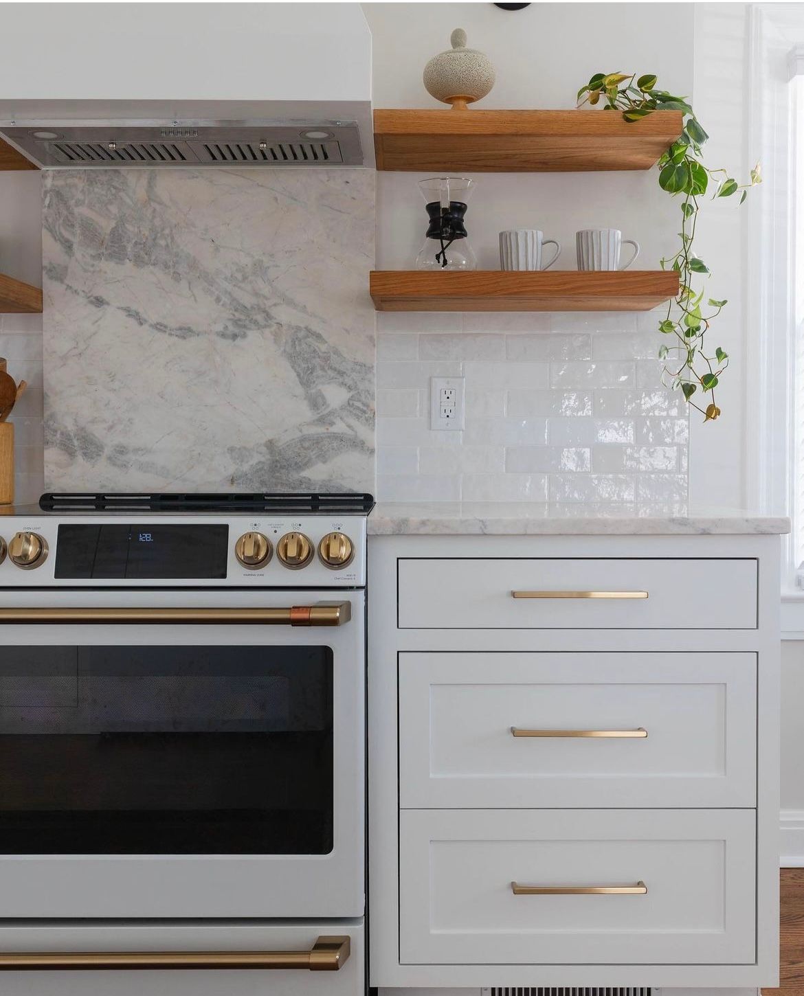 A kitchen with a white stove , white cabinets , and wooden shelves.