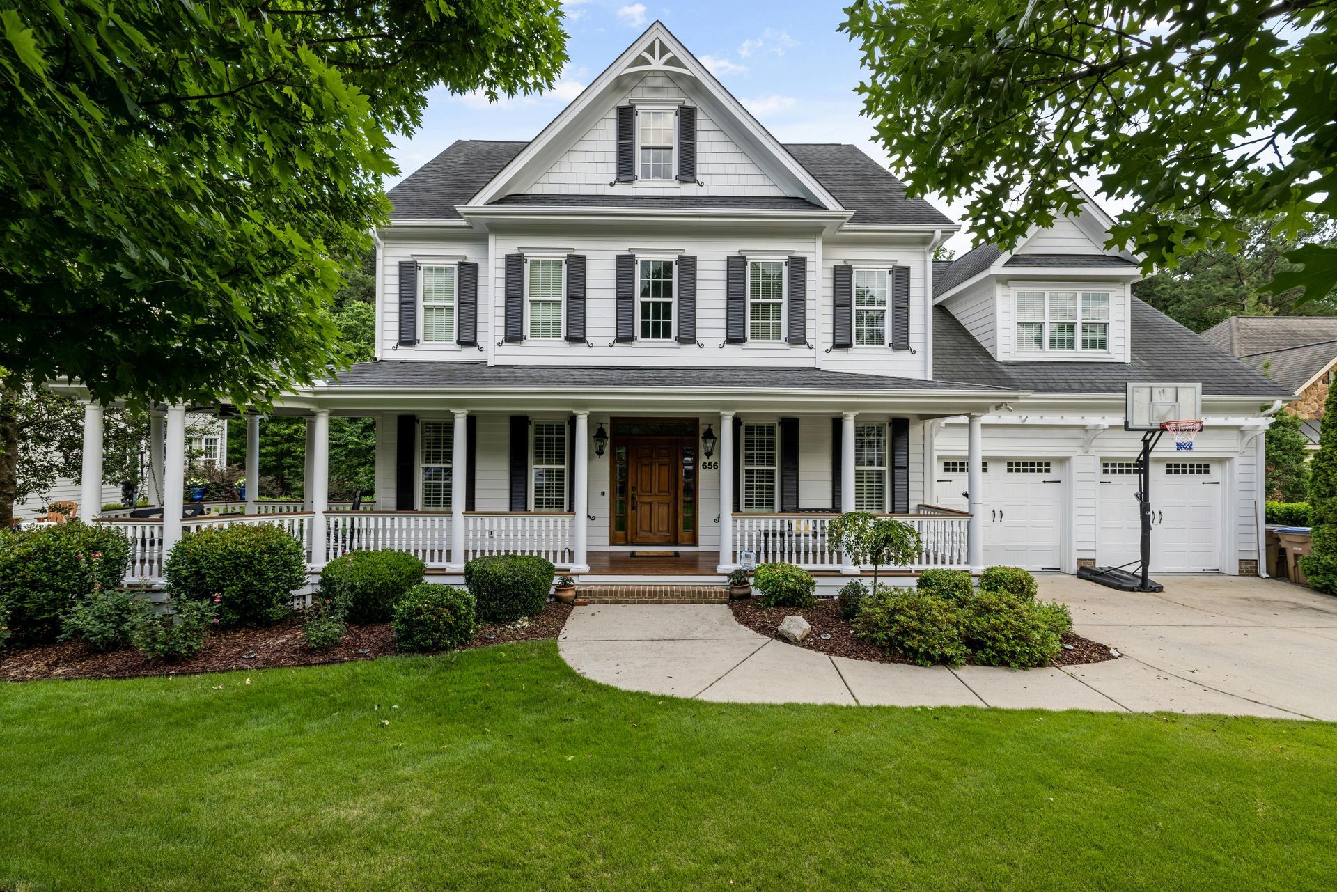A large white house with black shutters and a large porch.