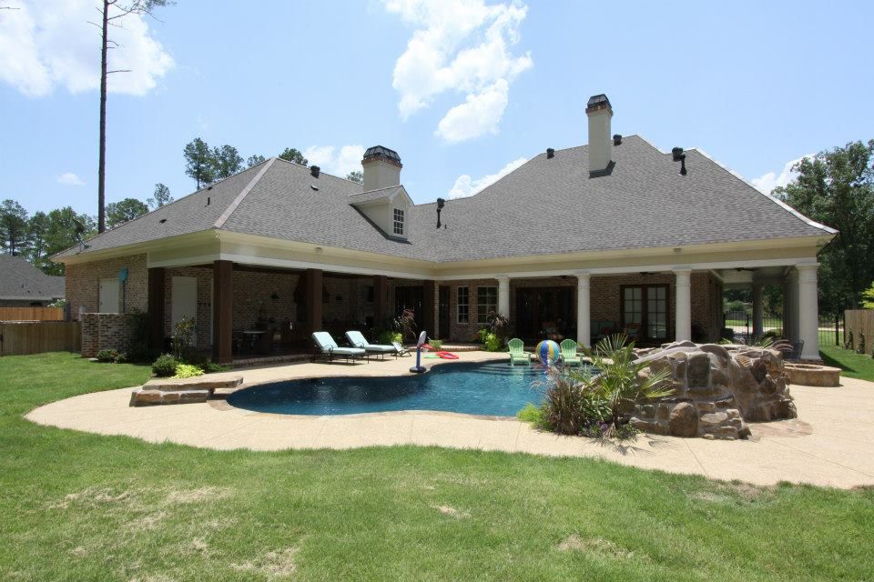 Backyard patio with a pool, lounge chairs, and a large house with a covered porch