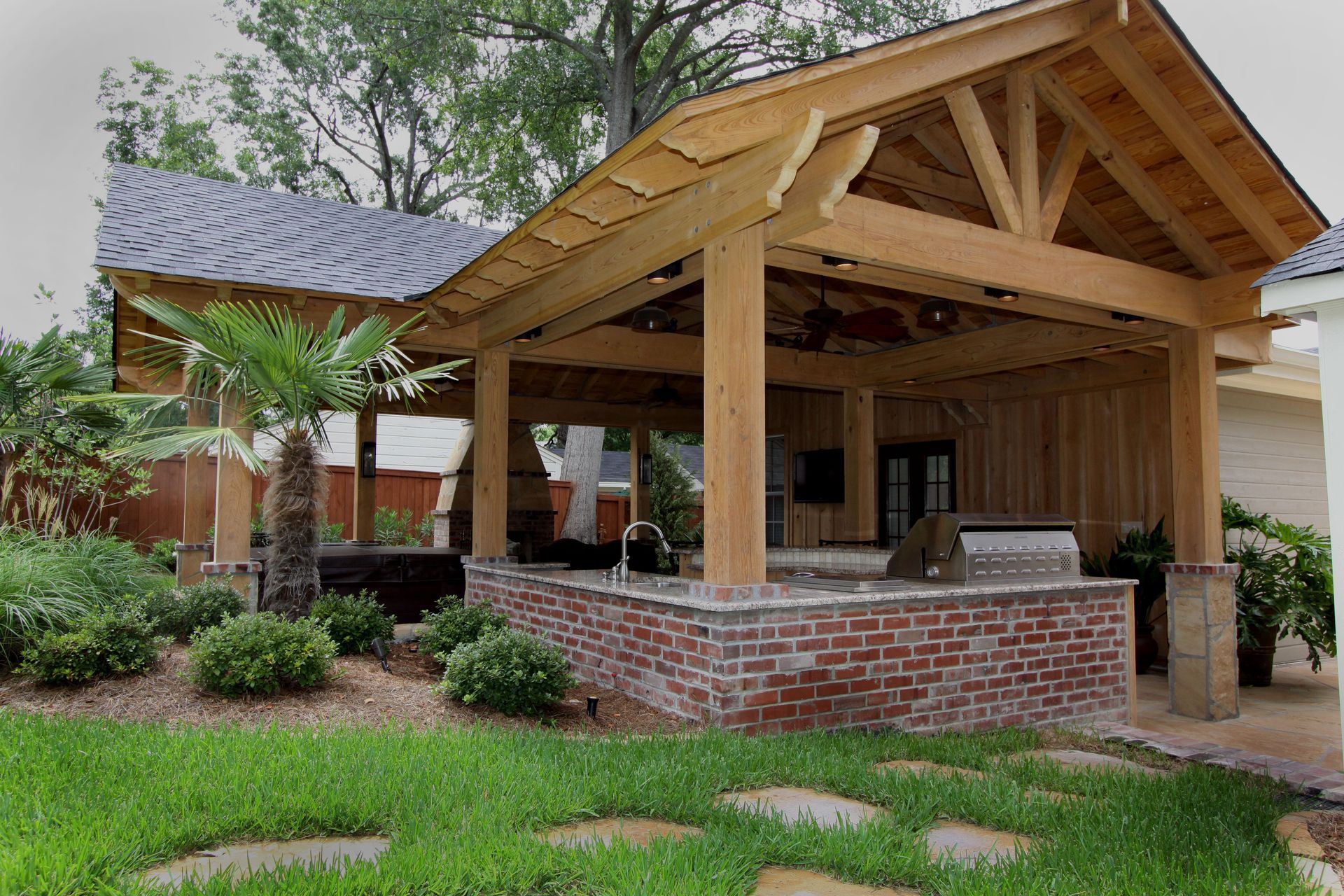 Wooden pavilion with brick base and shingled roof in a landscaped garden area