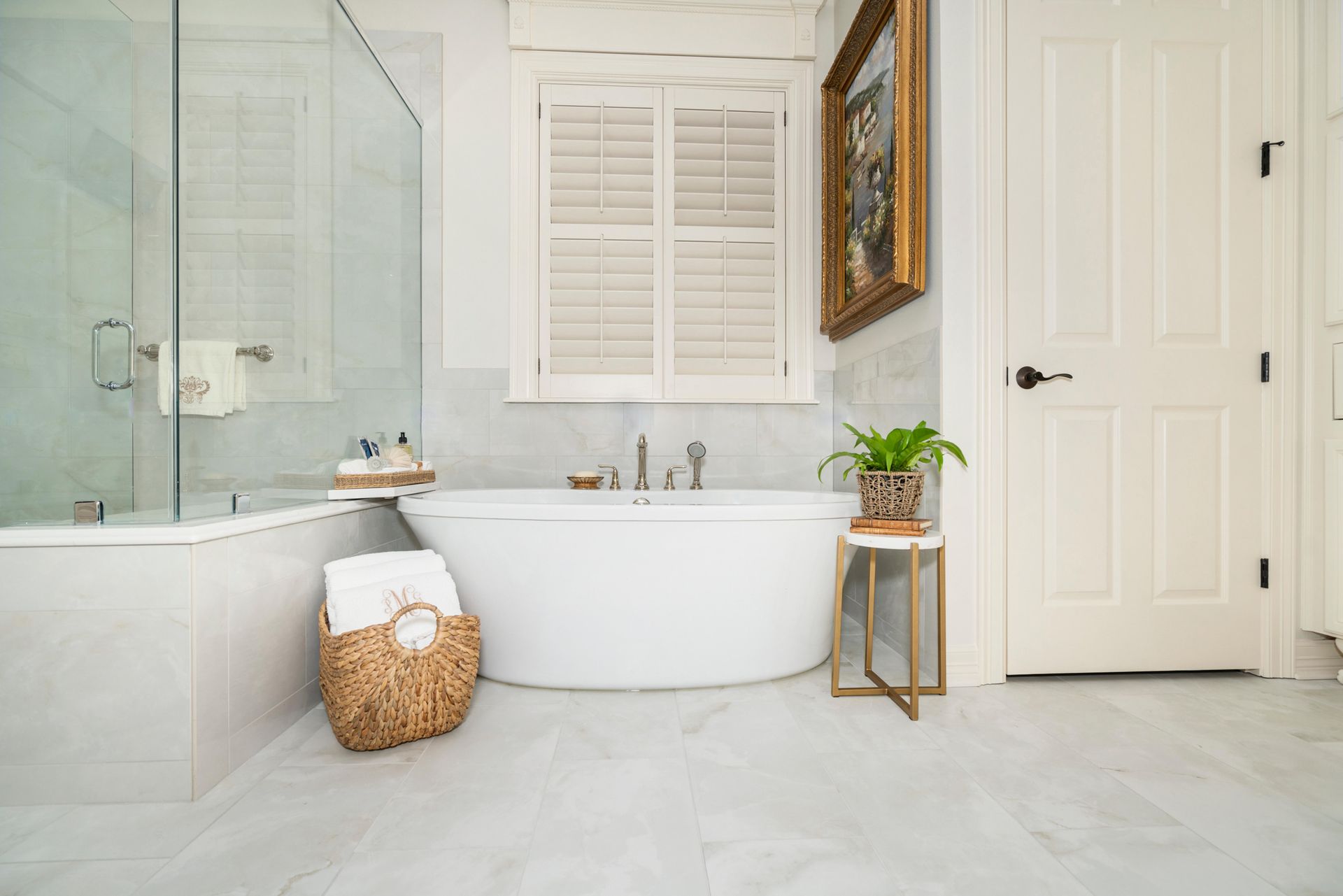 Bright modern bathroom with a soaking tub, glass shower, white tile, and a potted plant by the door