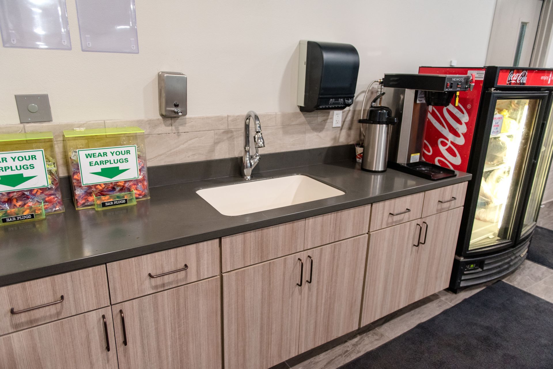 Break room counter with sink, candy jars, paper towel dispenser, Coca-Cola fridge, and display cooler