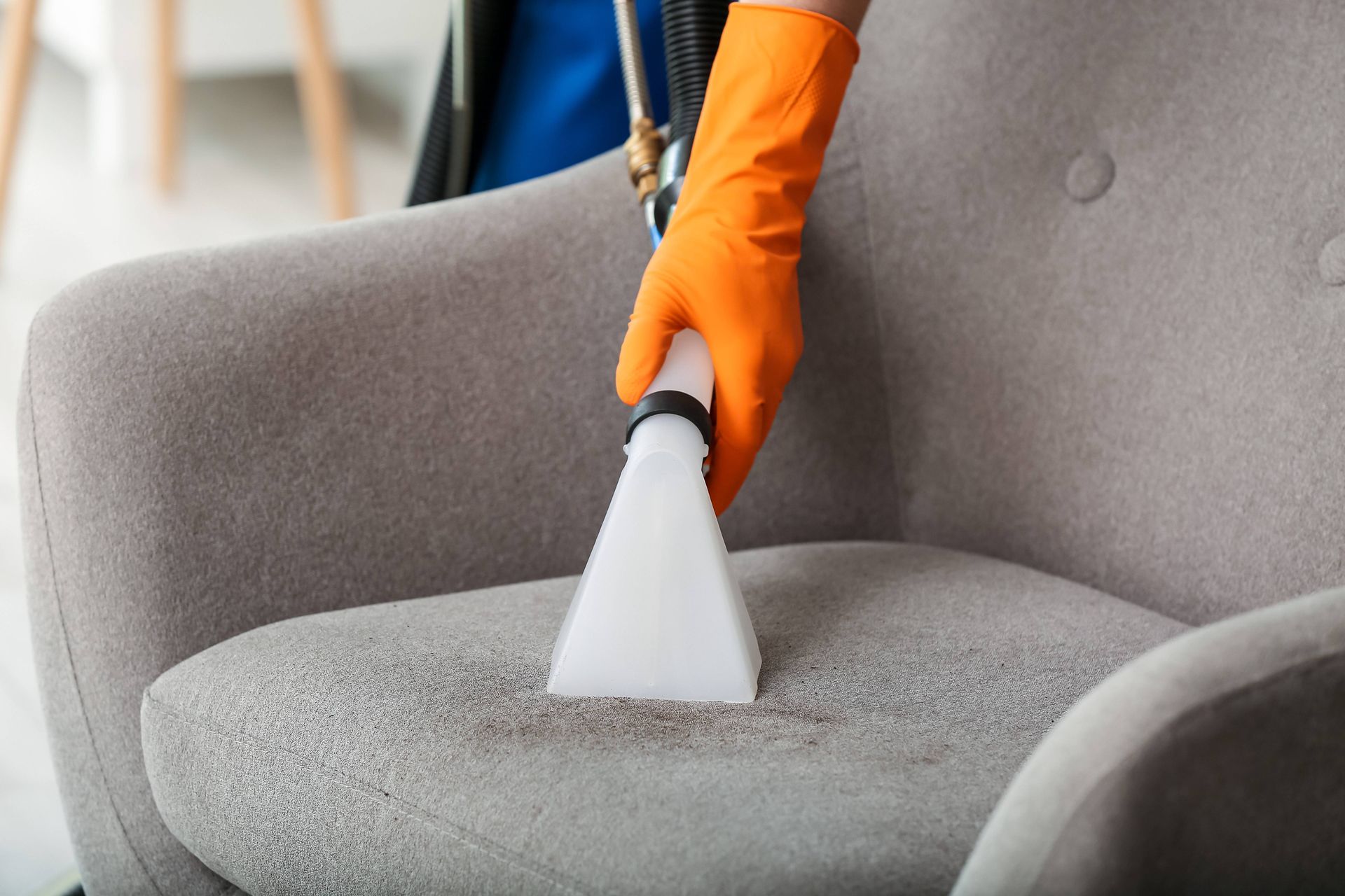 A person is cleaning a chair with a vacuum cleaner.