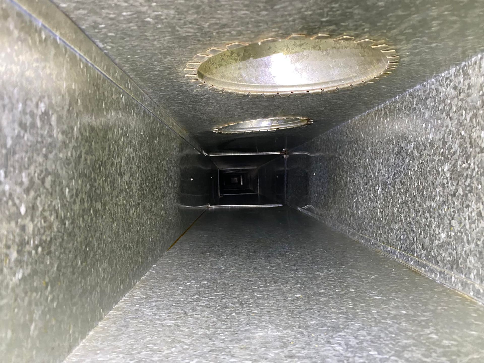 Looking down a metal duct with holes in it.