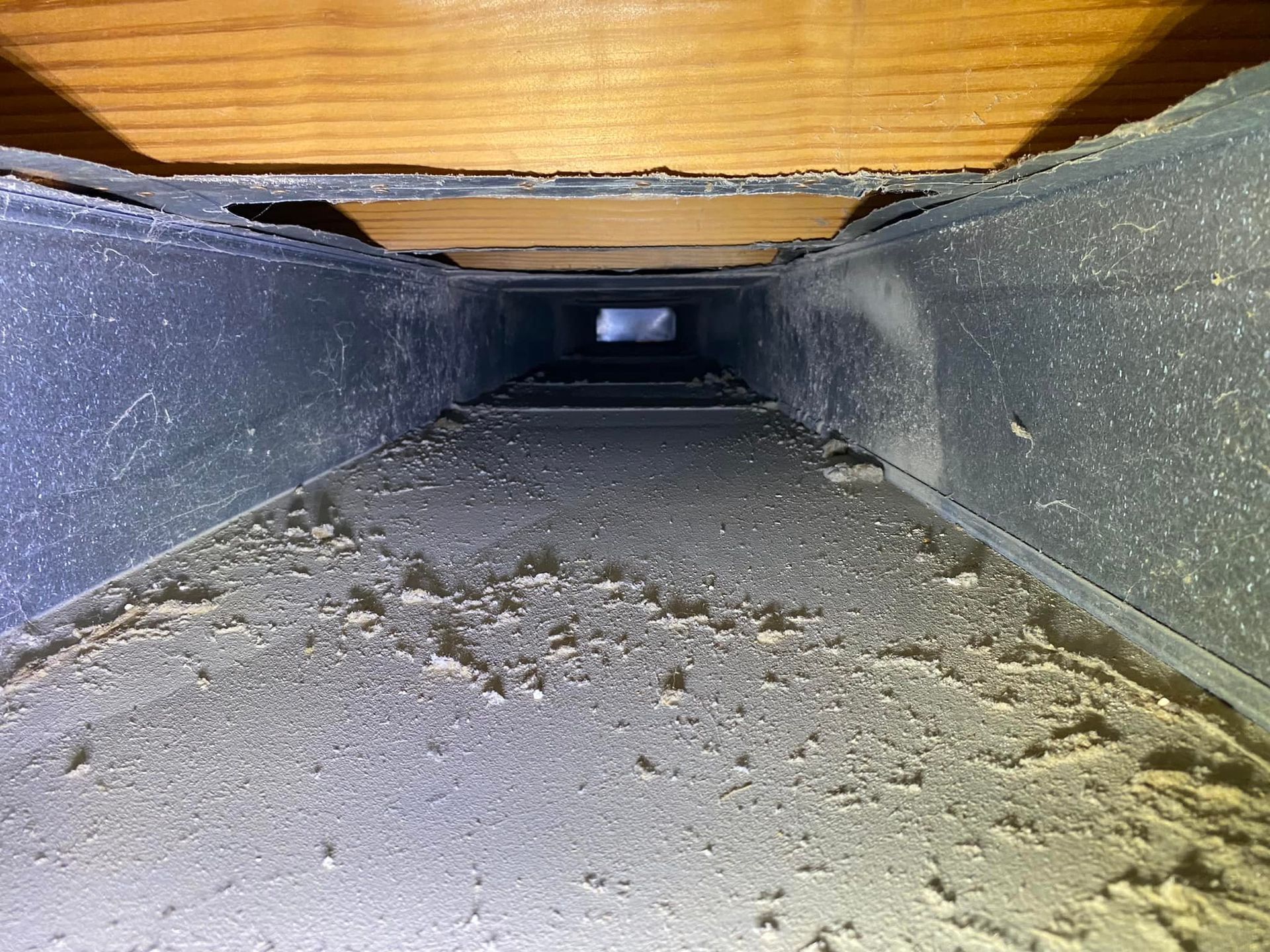 A dirty air duct with a hole in the middle of it.