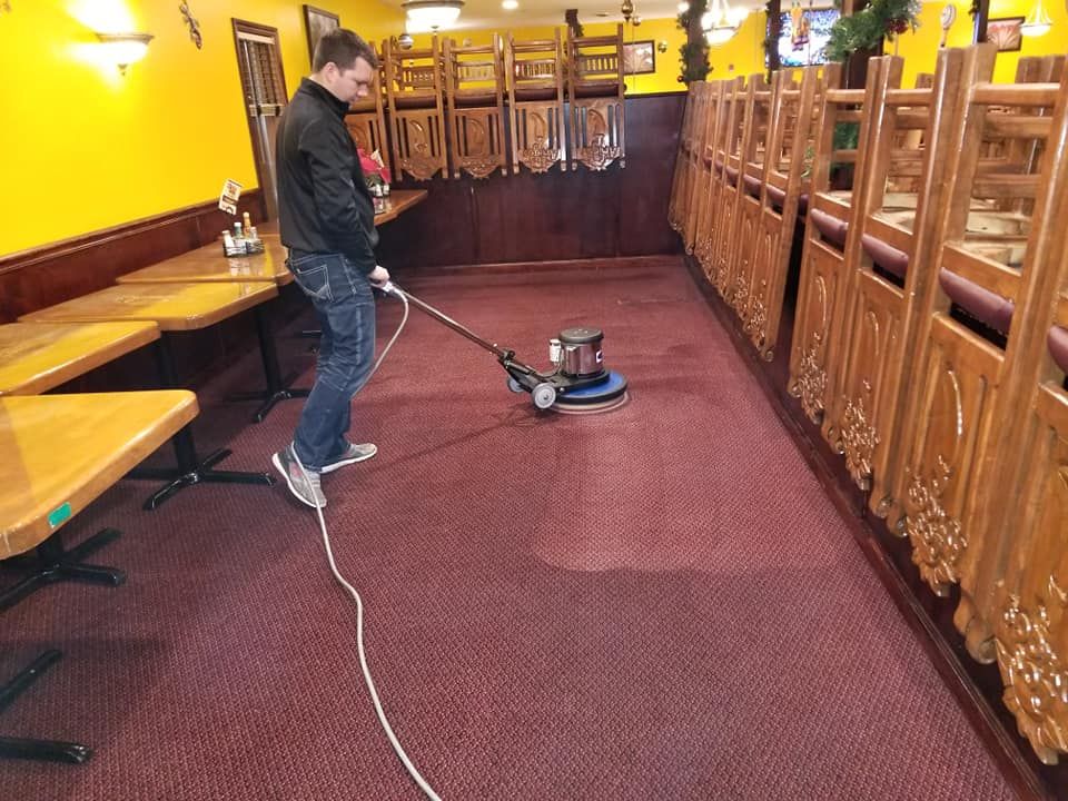 A man is cleaning the carpet in a restaurant