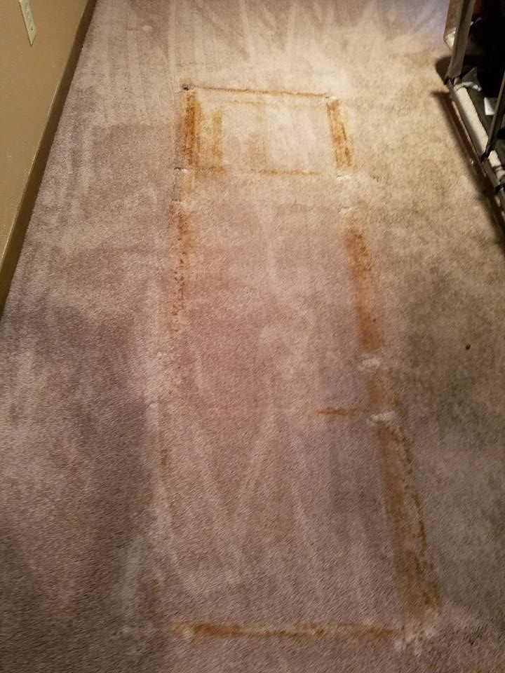 A dirty carpet in a hallway with a hole in it.