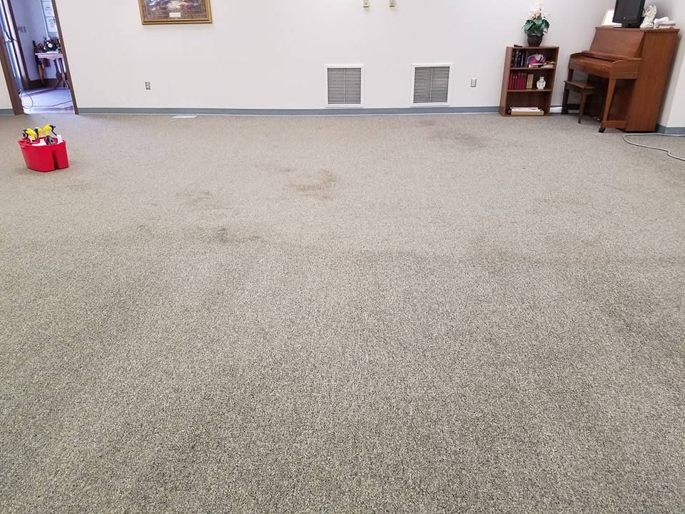 A large carpeted room with a piano in the background