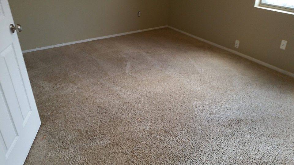 An empty bedroom with a carpeted floor and a window.