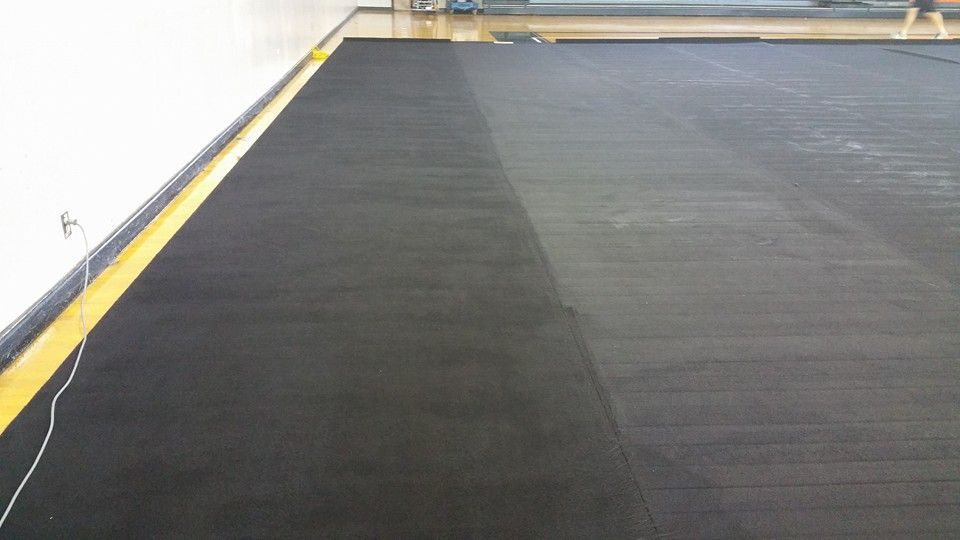 A black rubber floor with a yellow border in a room.