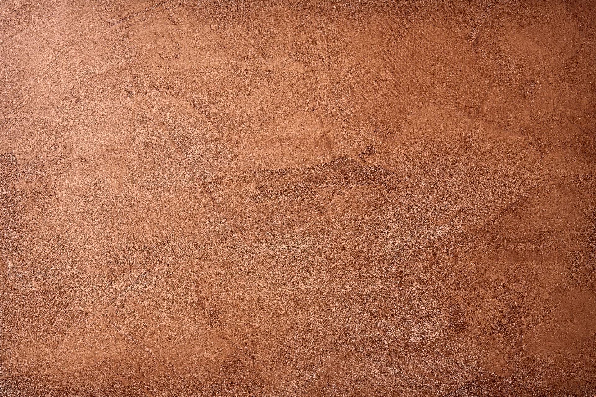 Strukturierte, rotbraune Wand mit Farbvariationen und einigen hellen Bereichen.