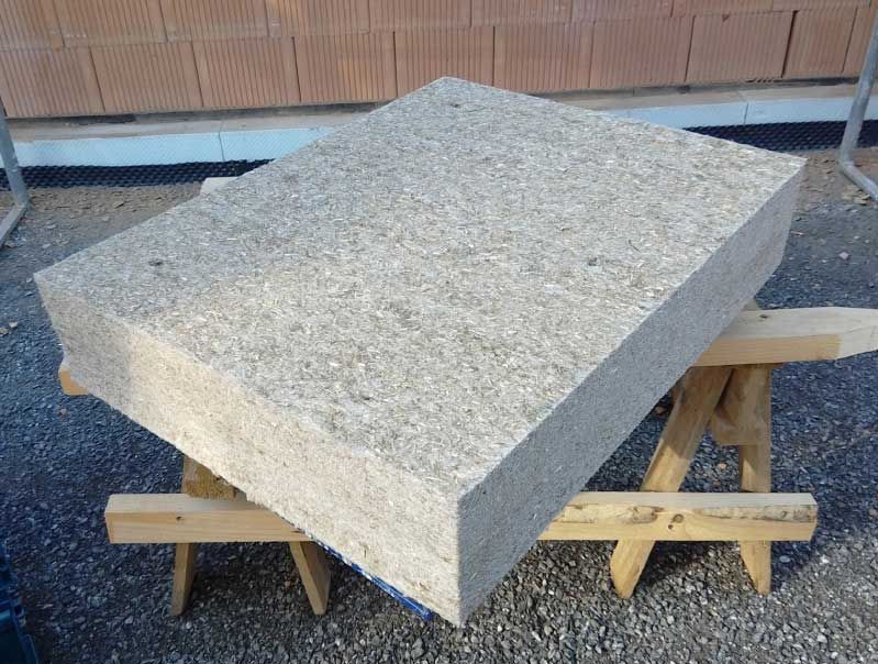 Eine rechteckige, helle Dämmplatte liegt im Außenbereich auf zwei hölzernen Sägeböcken.