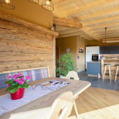 Gemütliches Esszimmer mit Holzwänden, gedecktem Tisch mit Blumen.