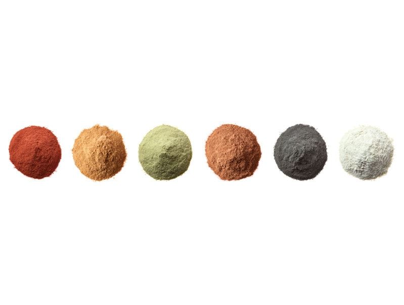 Sechs bunte Lehm Farben Pgmente: Rot, Orange, Grün, Rost, Grau und Weiß, horizontal aufgereiht.