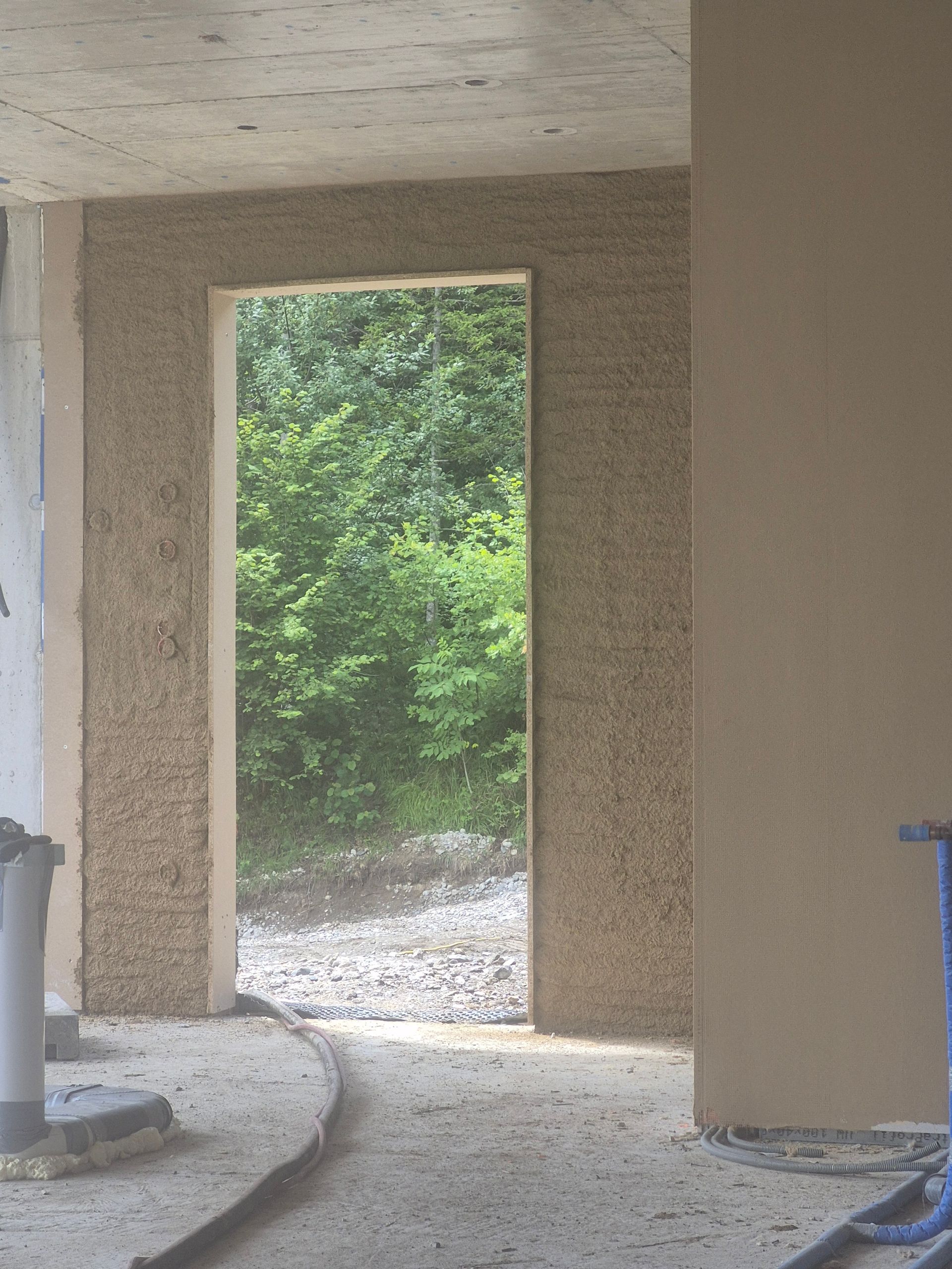 Innentür in einem unfertigen Gebäude mit Blick auf grüne Bäume und einen Kiesweg.