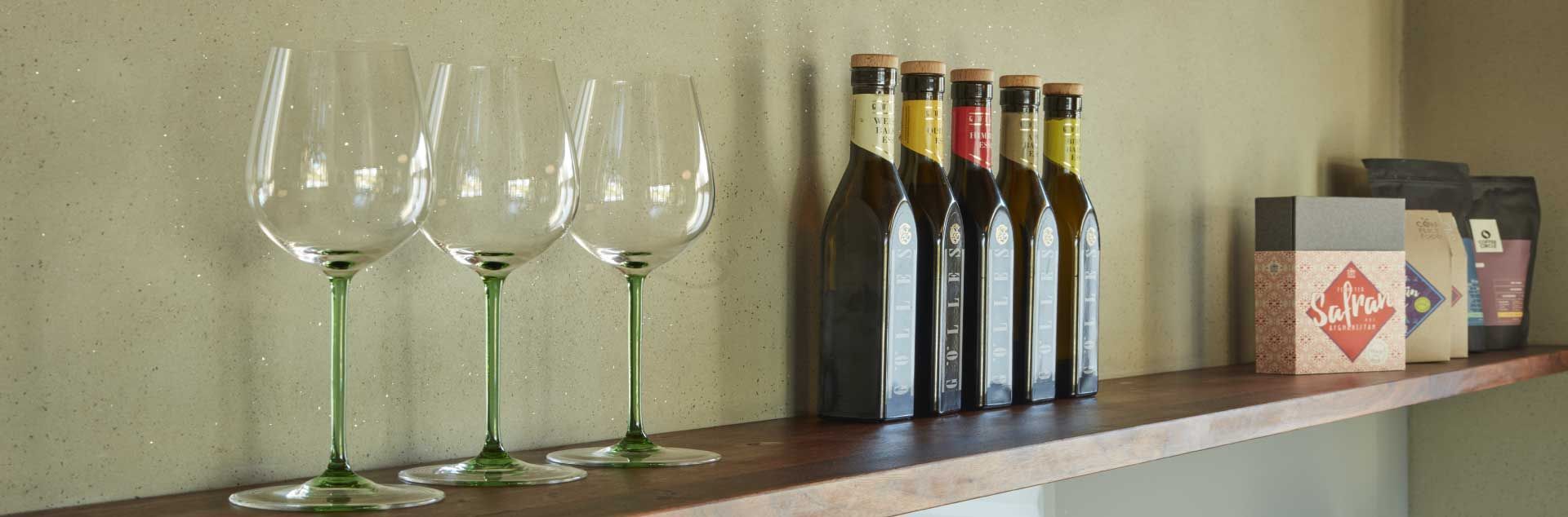 Weingläser und -flaschen auf einem Holzregal vor einer hellgrünen Wand.