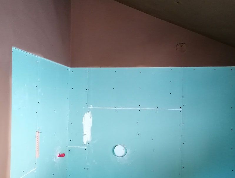 Innenecke eines im Bau befindlichen Raums; blaue Trockenbauwand, rosa gestrichene Wand.