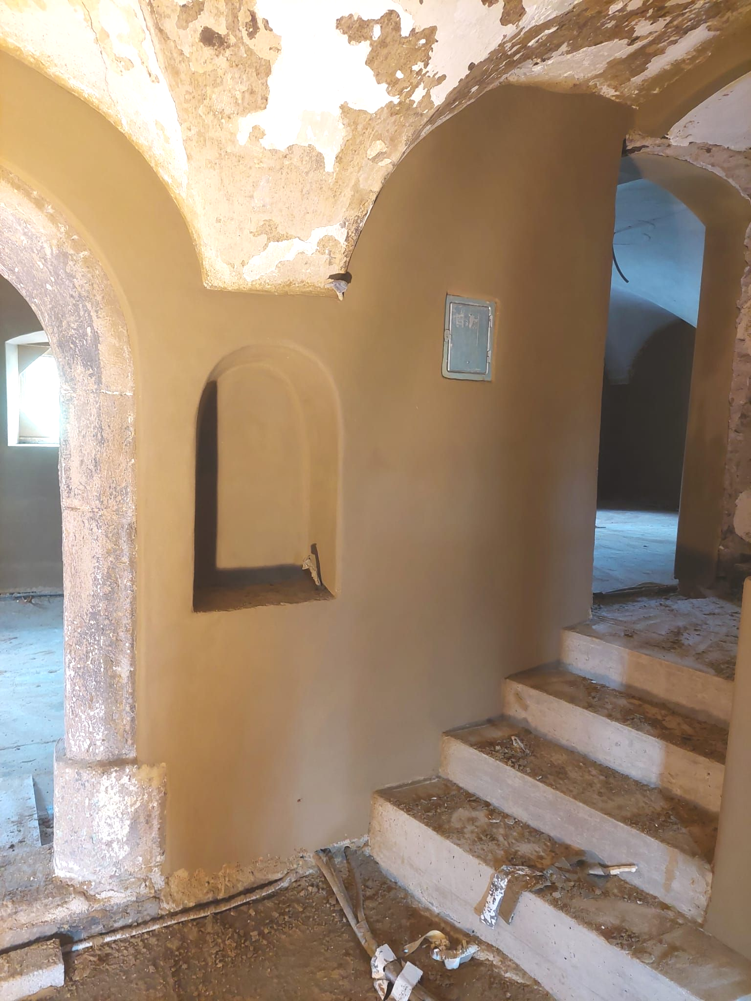 Innenraum mit gewölbten Türen, Treppe und beigen Wänden wird gerade renoviert.