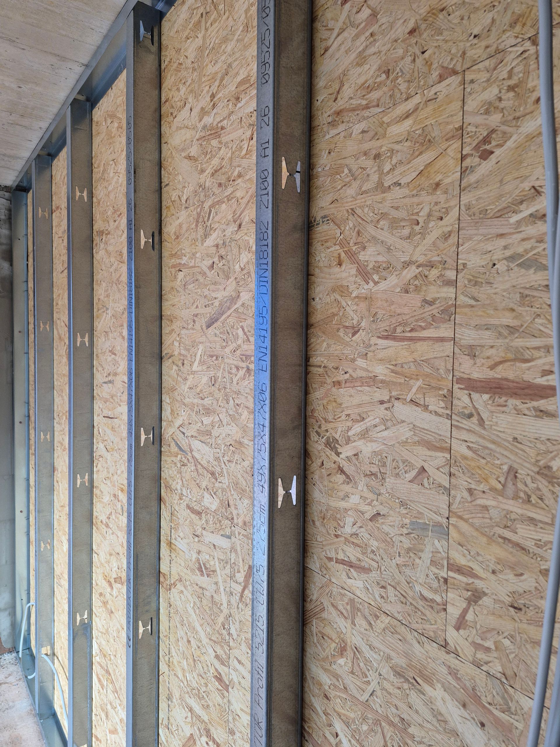 An einer OSB-Wand montierte Metallständer. Bauarbeiten im Gange.