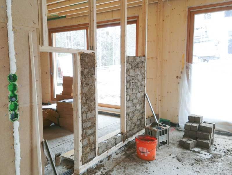 Innenansicht eines im Bau befindlichen Hauses mit Holzrahmen und Wänden aus Lehmsteinen.