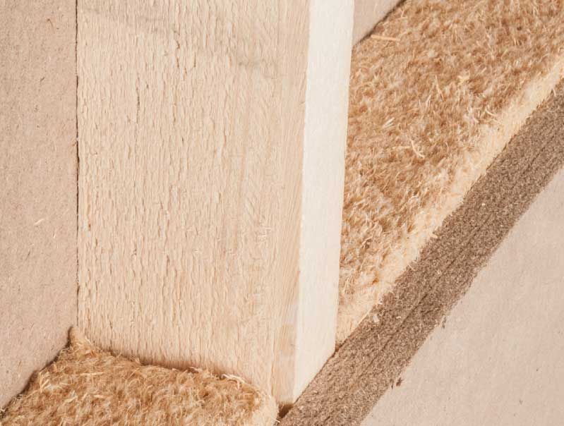 Nahaufnahme der Baumaterialien: Holzpfosten und braune Isolierung, die eine Ecke bilden.