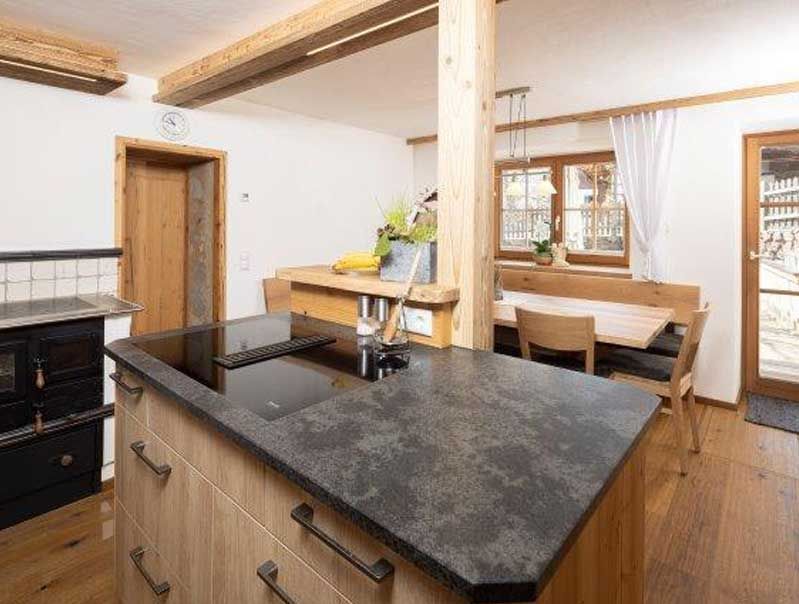 Gemütliche Küche mit Holzakzenten, einschließlich einer Kochinsel mit Kochfeld und einem Essbereich.