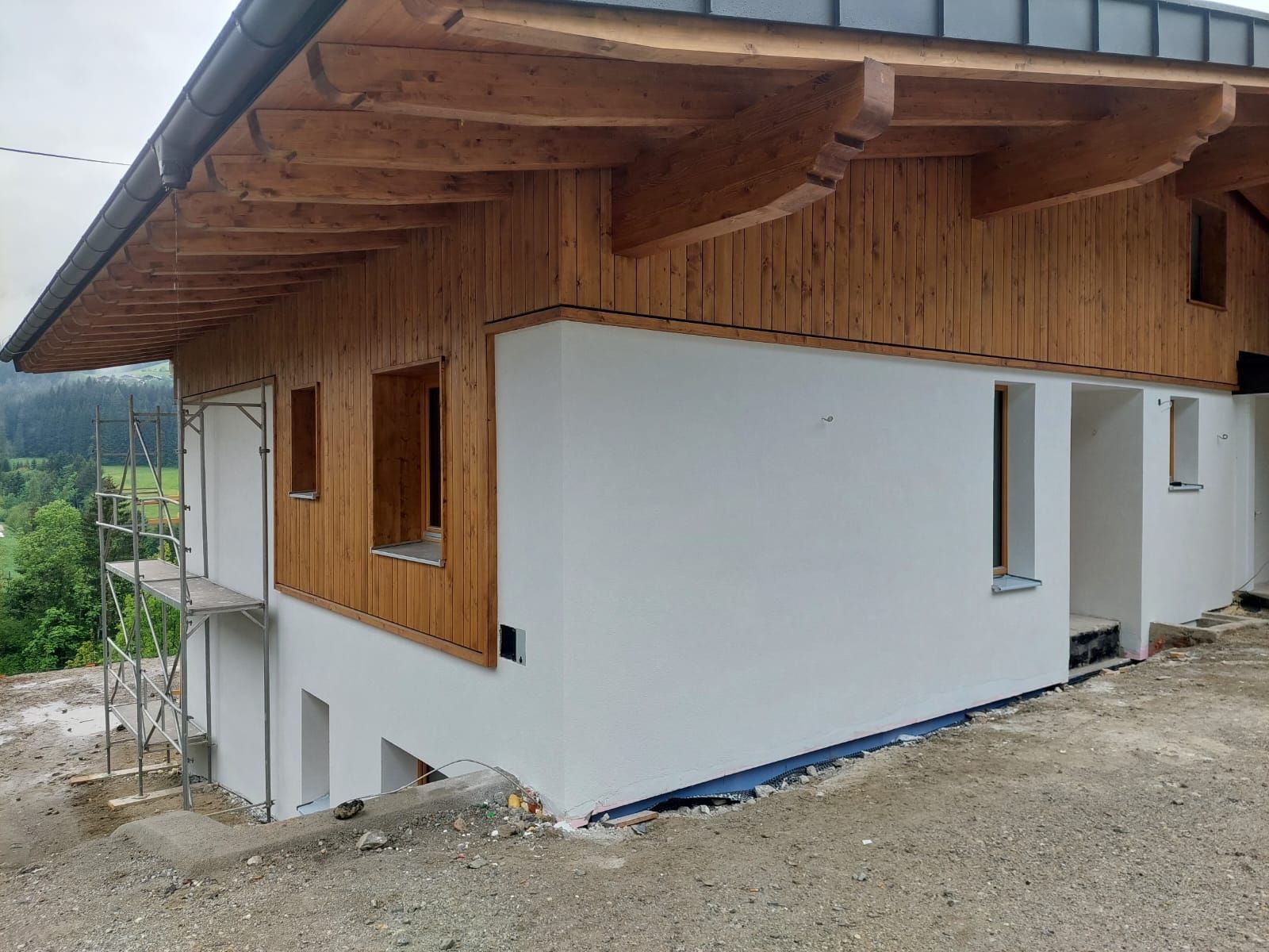 Außenansicht eines teilweise fertiggestellten Hauses mit Holzverkleidung.