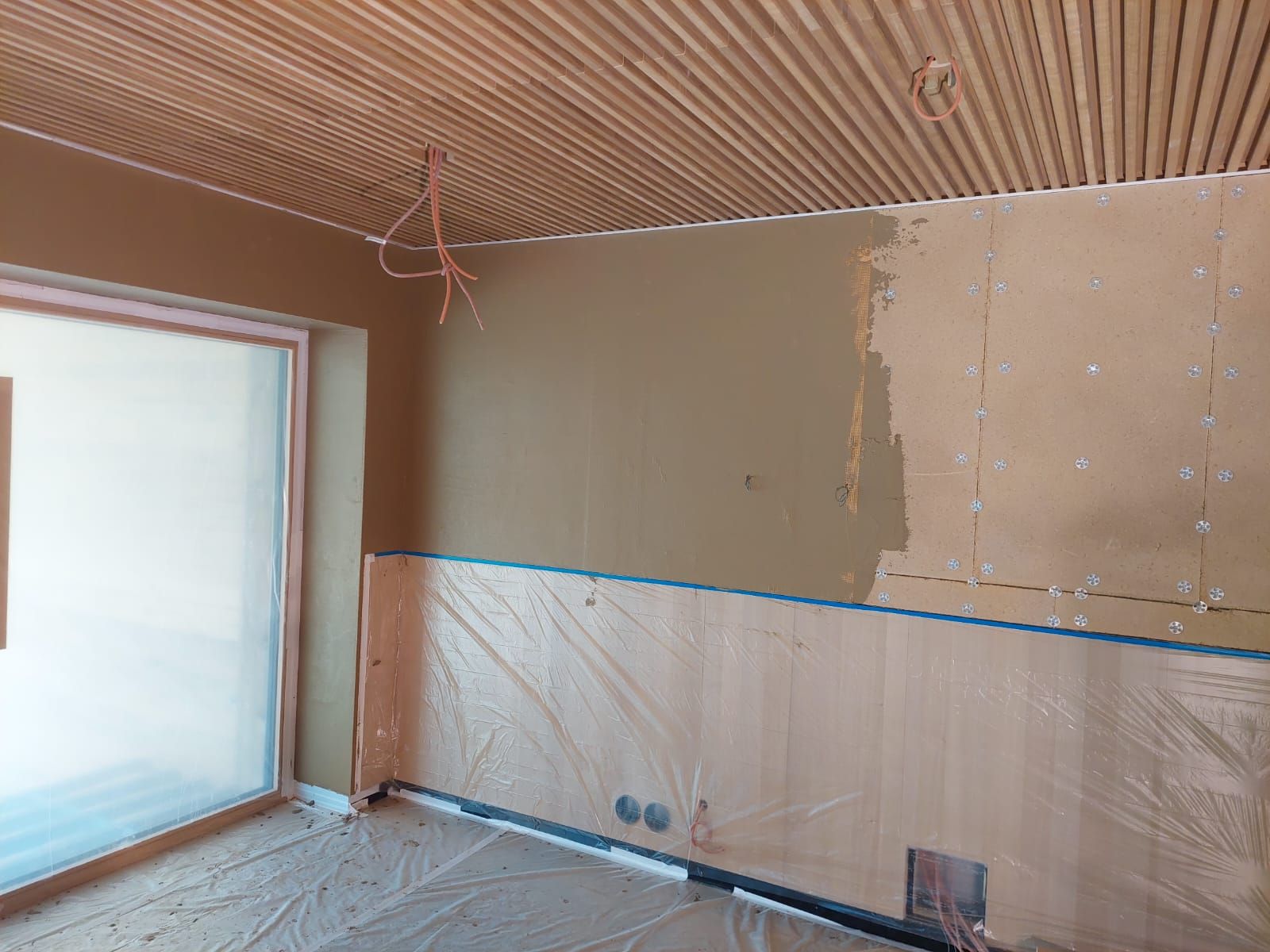 Zimmer wird renoviert, mit hellbraunen Wänden, Holzvertäfelung und gewellter Decke.