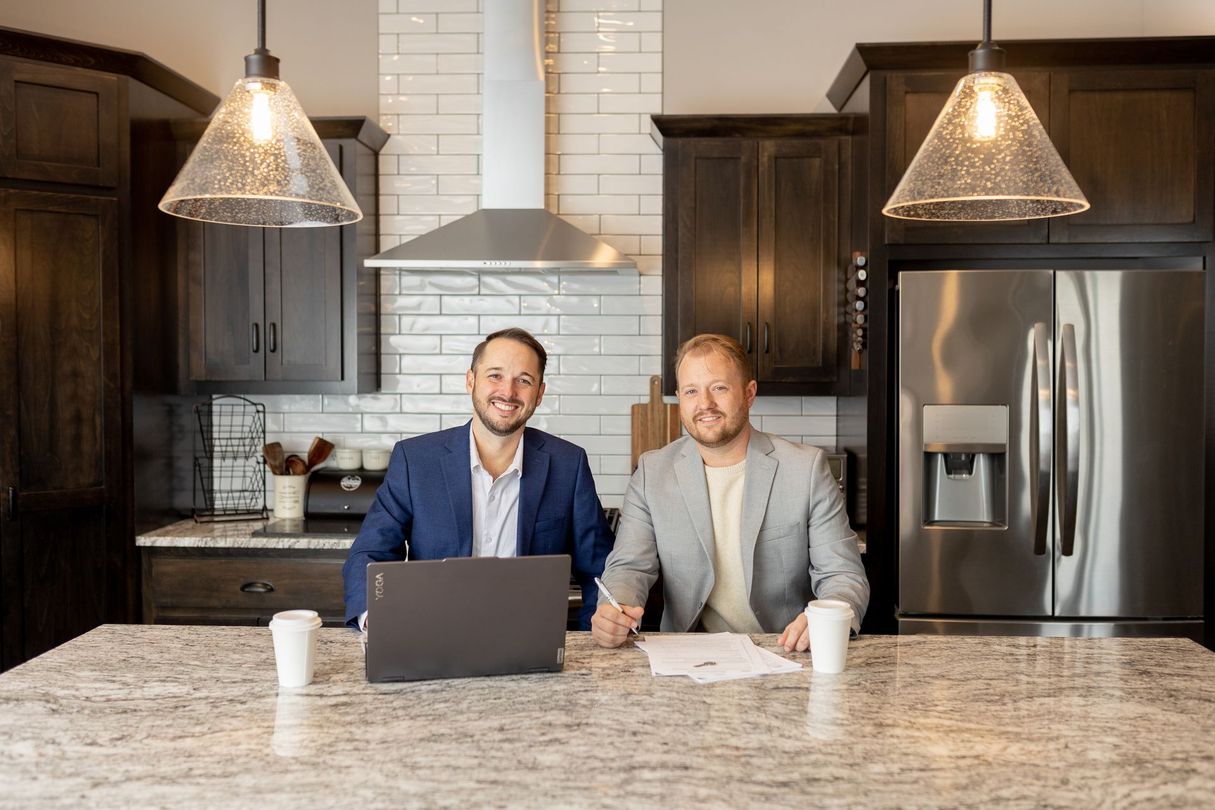 Modern kitchen and dining area with wood, white, and gold accents, featuring table and chairs.