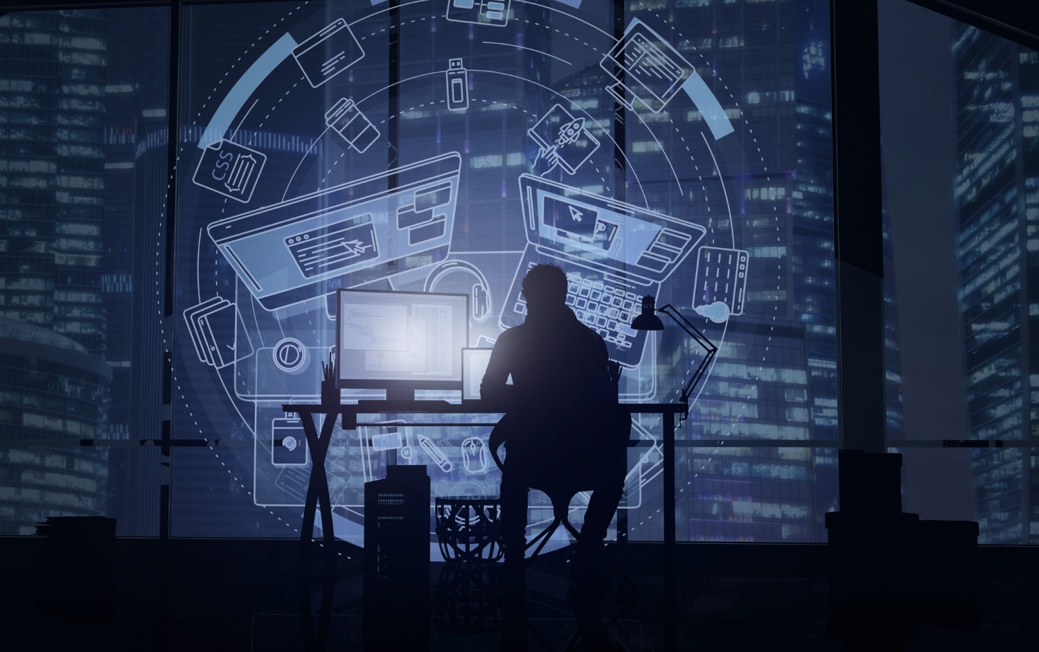 A man is sitting at a desk in front of a computer screen.