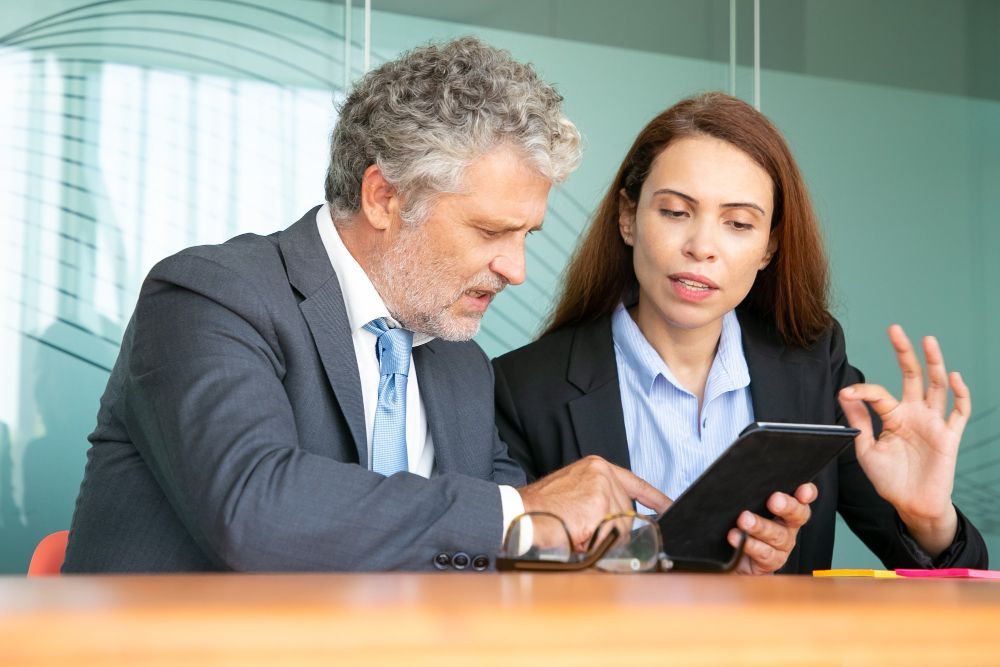 Two business professionals in suits reviewing documents, discussing strategy.