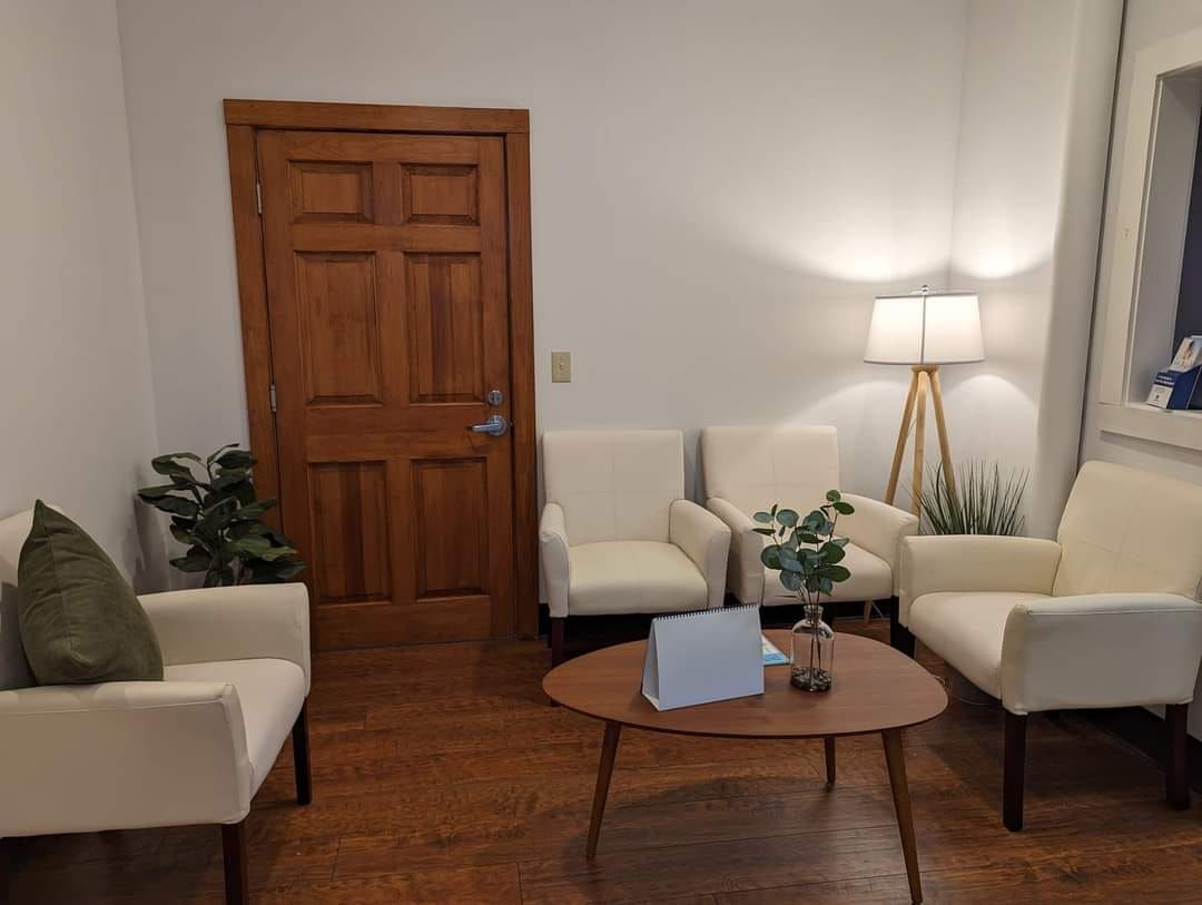 Man reclining on a couch, looking up thoughtfully, with blurred figure of another person in background.