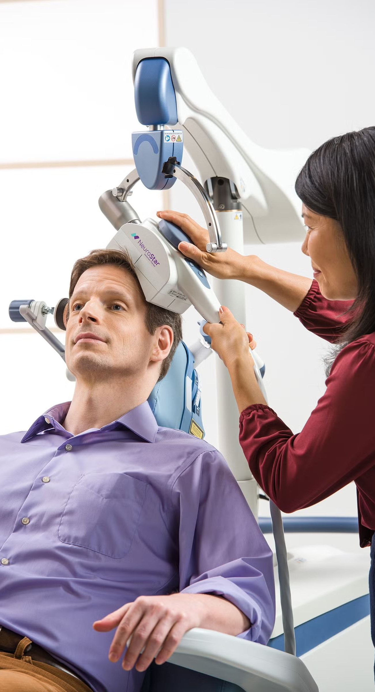 Healthcare worker adjusting a medical device on a reclining patient in a clinic setting