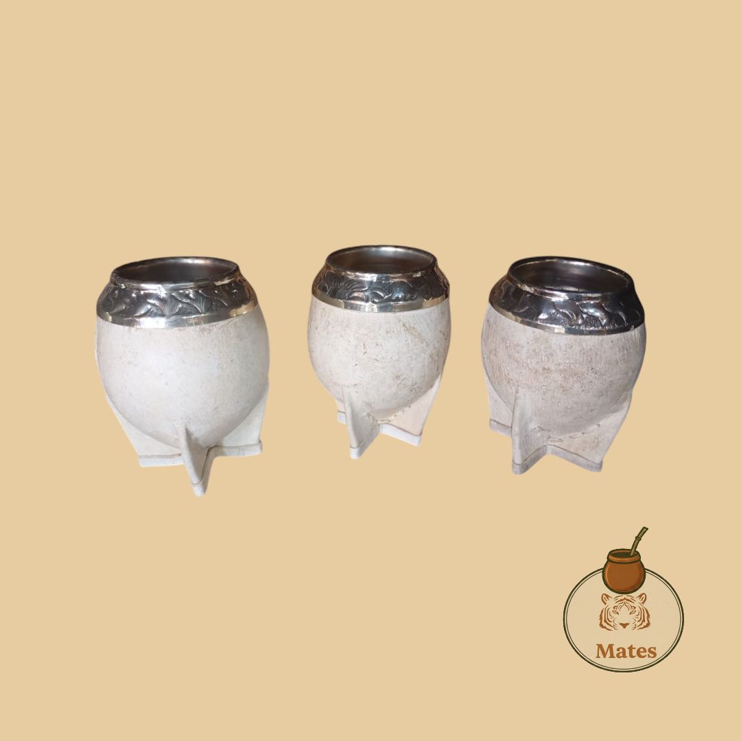 Tres calabazas de mate blancas con bordes plateados sobre un fondo tostado, con un logotipo de mate.