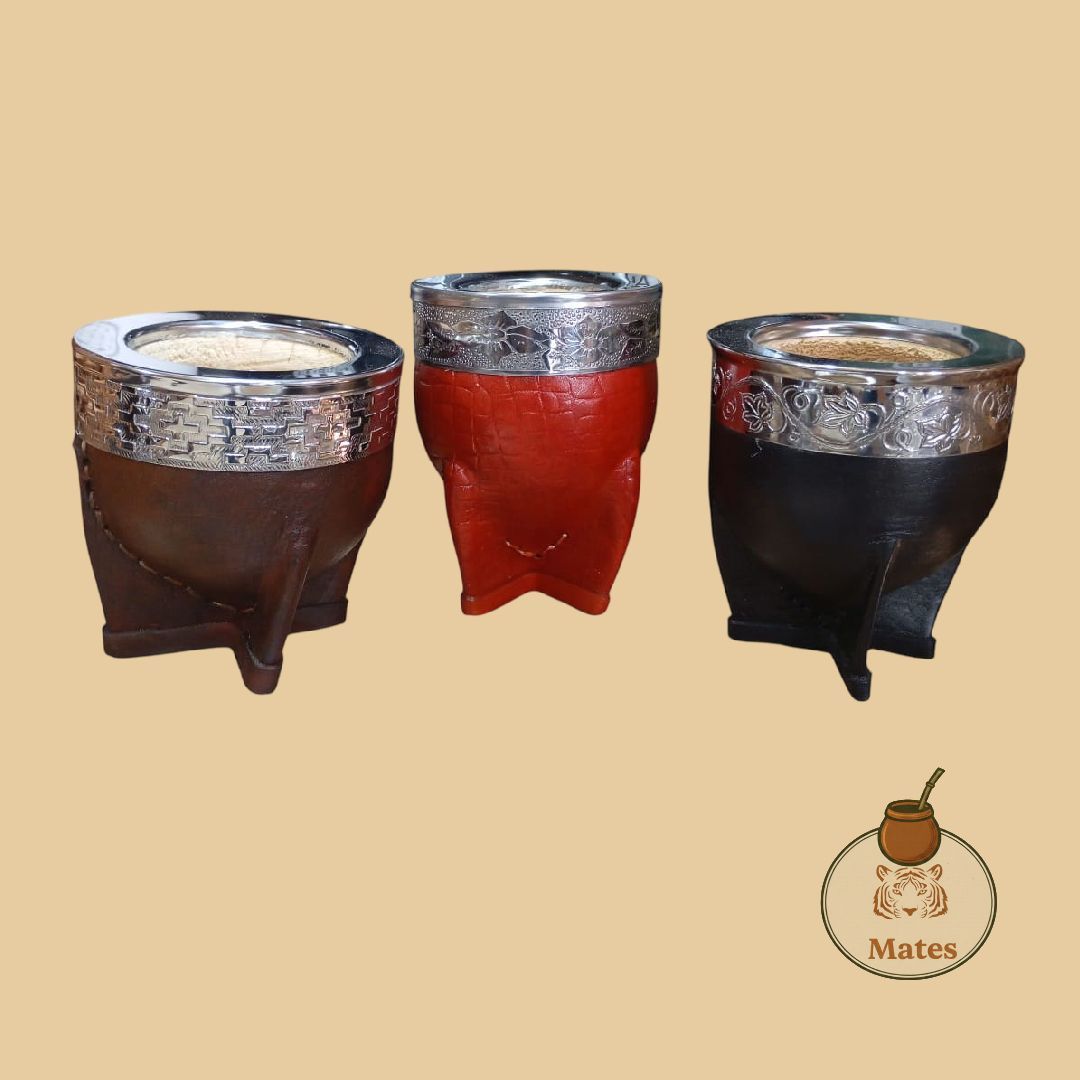 Tres calabazas de yerba mate en marrón, rojo y negro, cada una con ribete plateado, expuestas sobre un fondo neutro.