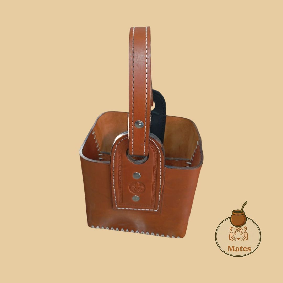 Cubo de cuero marrón con asa y costuras blancas.