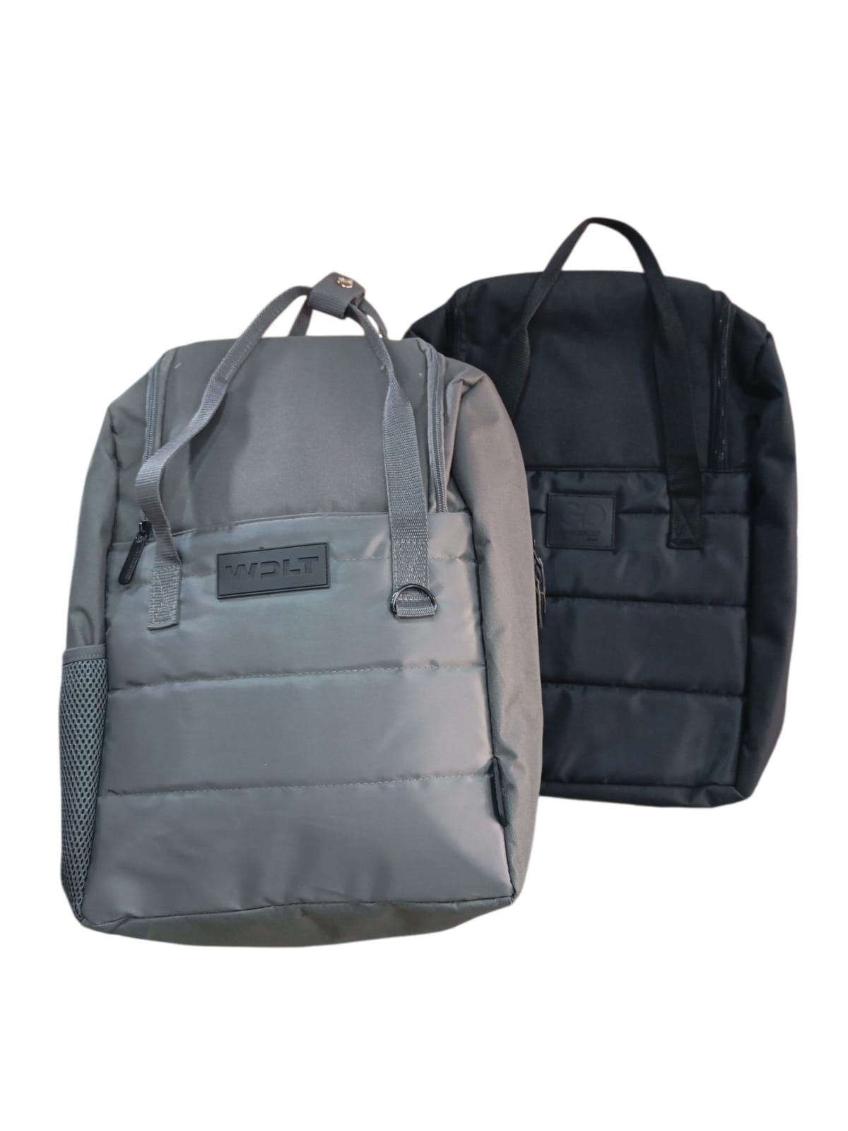 Dos mochilas acolchadas, una gris y otra negra, sobre fondo blanco. Tienen asas superiores y son rectangulares.