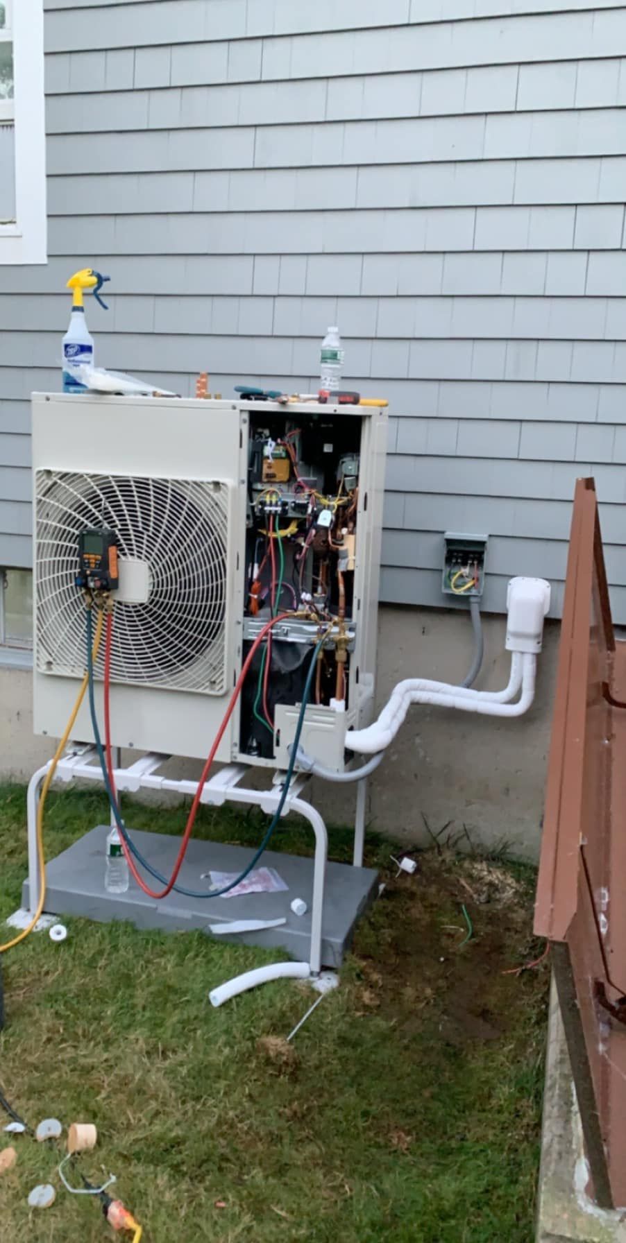 A heat pump is being installed on the side of a house.
