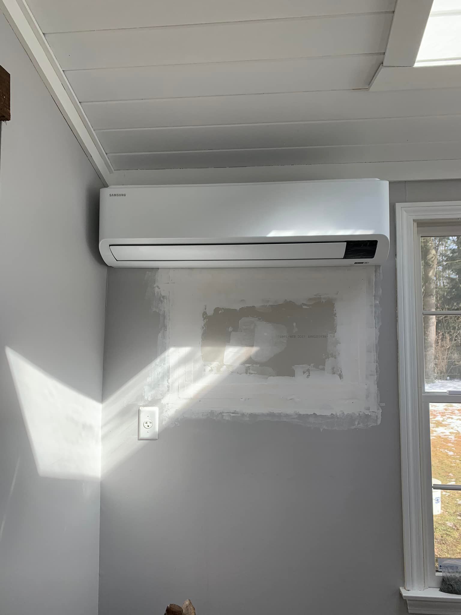 A room with a window and a wall mounted air conditioner.