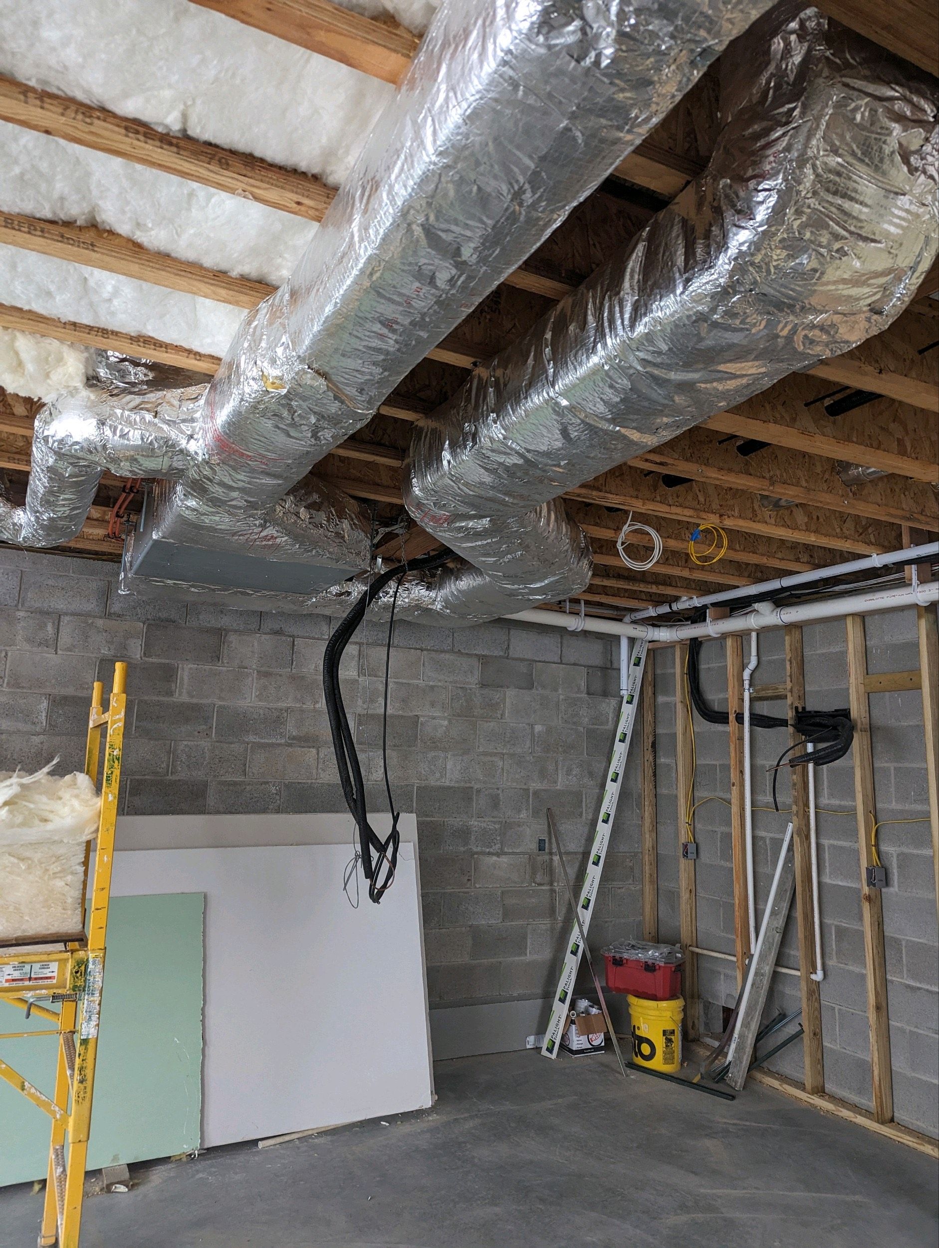A water heater is sitting in a basement next to a stone wall.