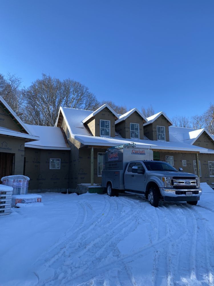 A truck is parked in front of a house covered in snow.