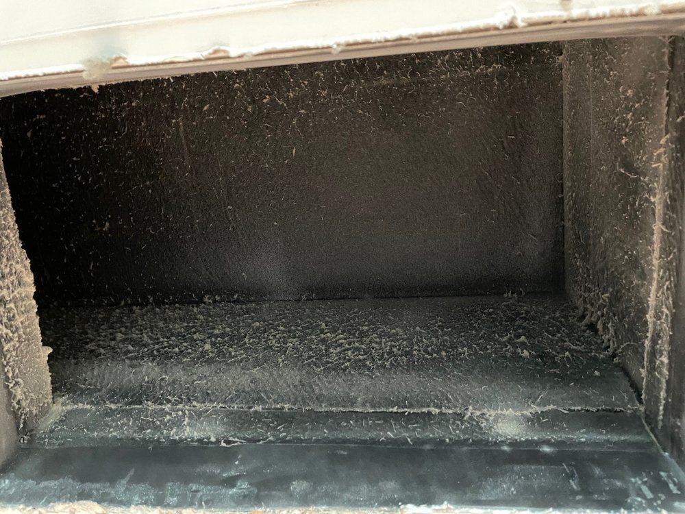 The inside of a dirty air vent with a lot of dust on it.