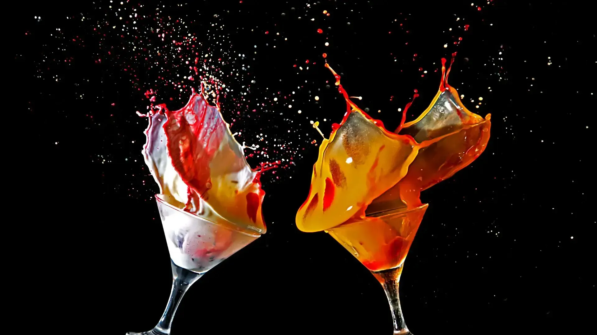 Two martini glasses with liquid splashing out of them on a black background