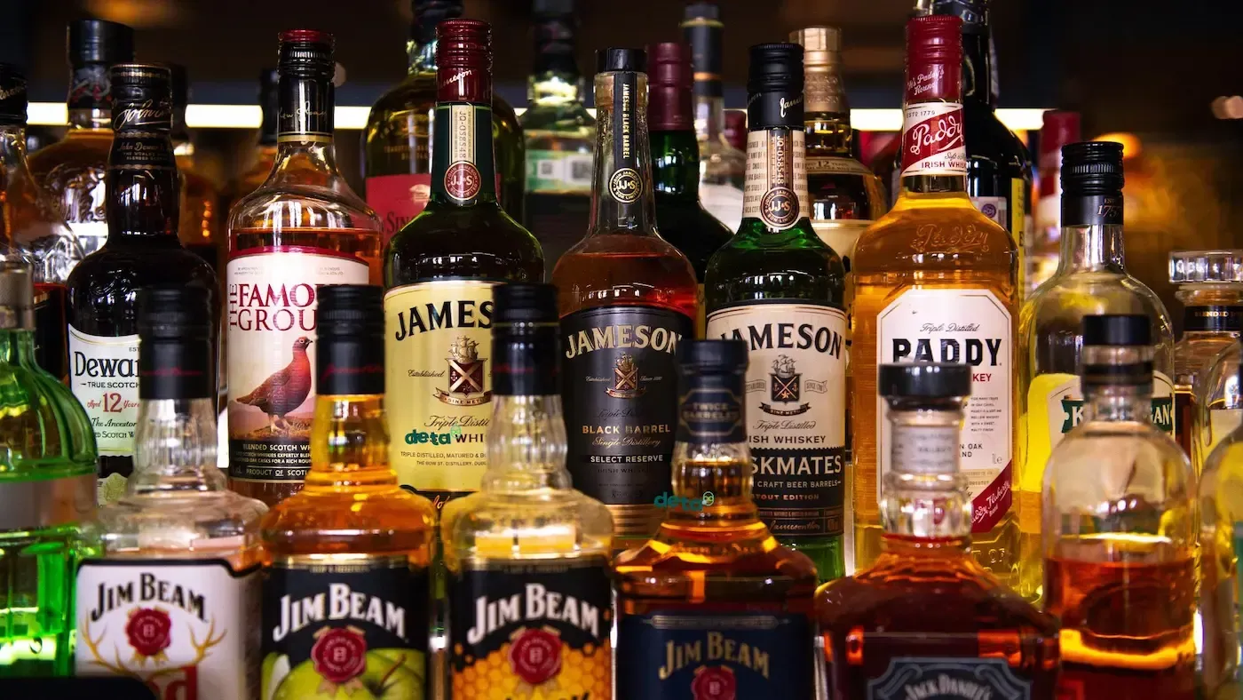 A row of bottles of liquor including jim beam and paddy