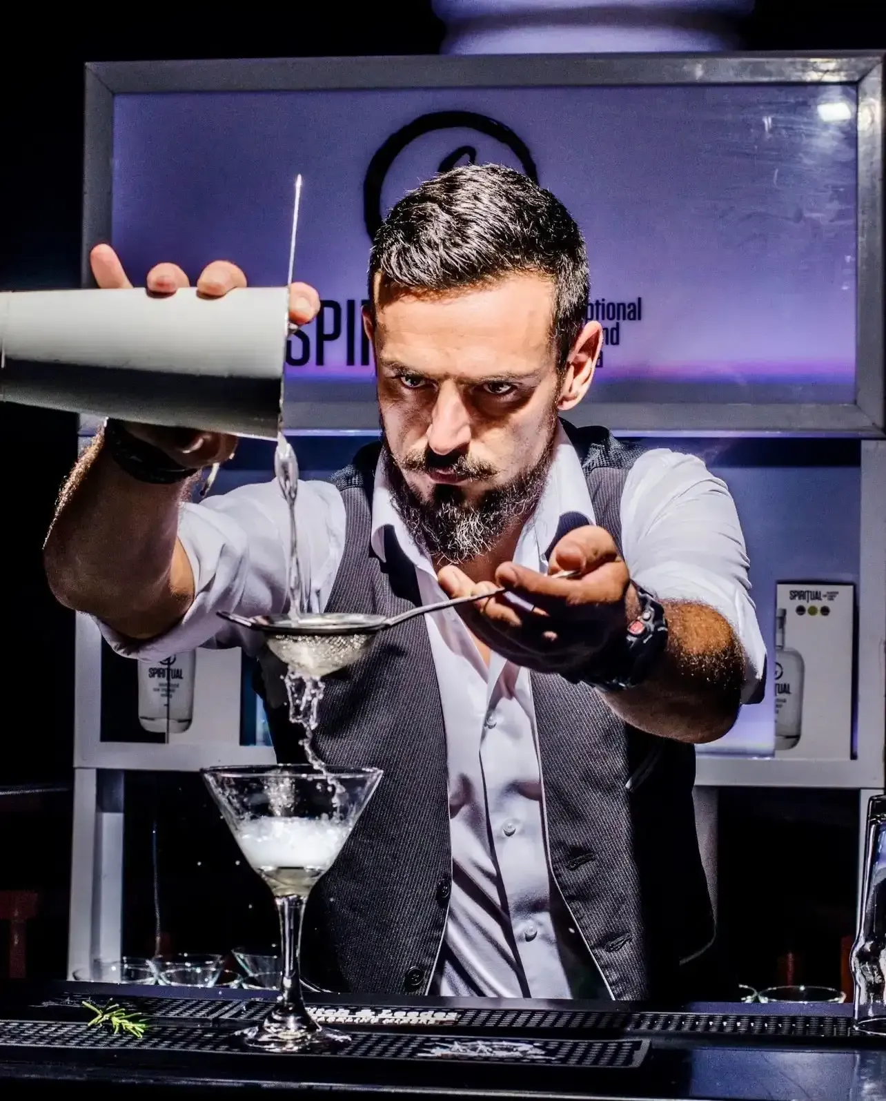 A bartender is pouring a drink into a martini glass