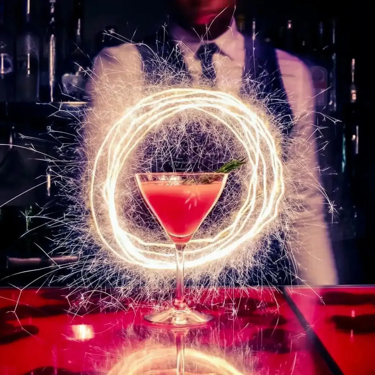 A man holding a martini with sparklers around it