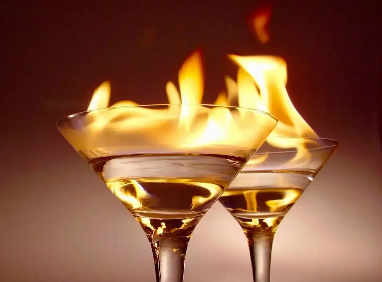 two martini glasses with flames coming out of them