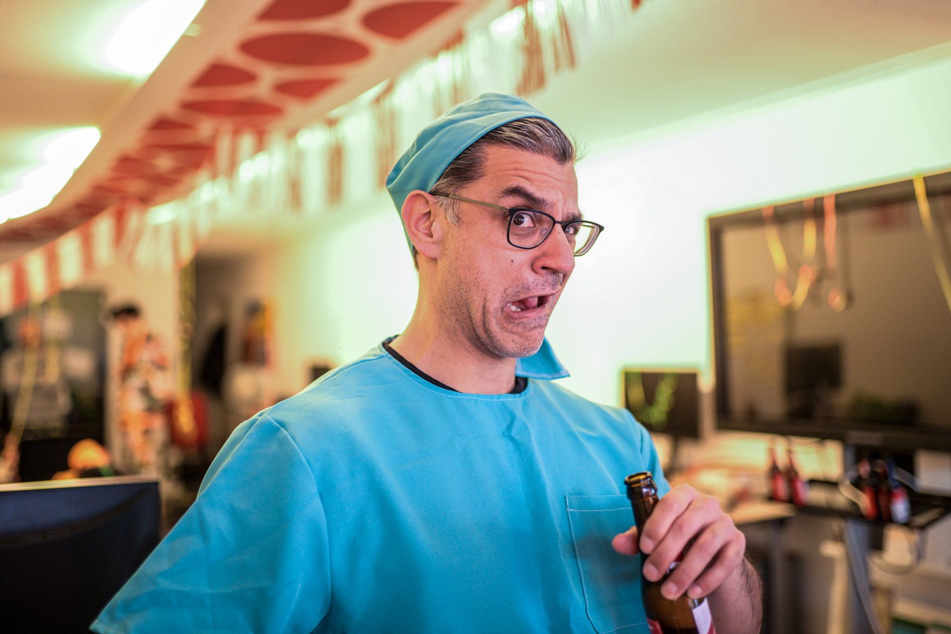 Een man verkleed als chirurg houdt een flesje bier vast.