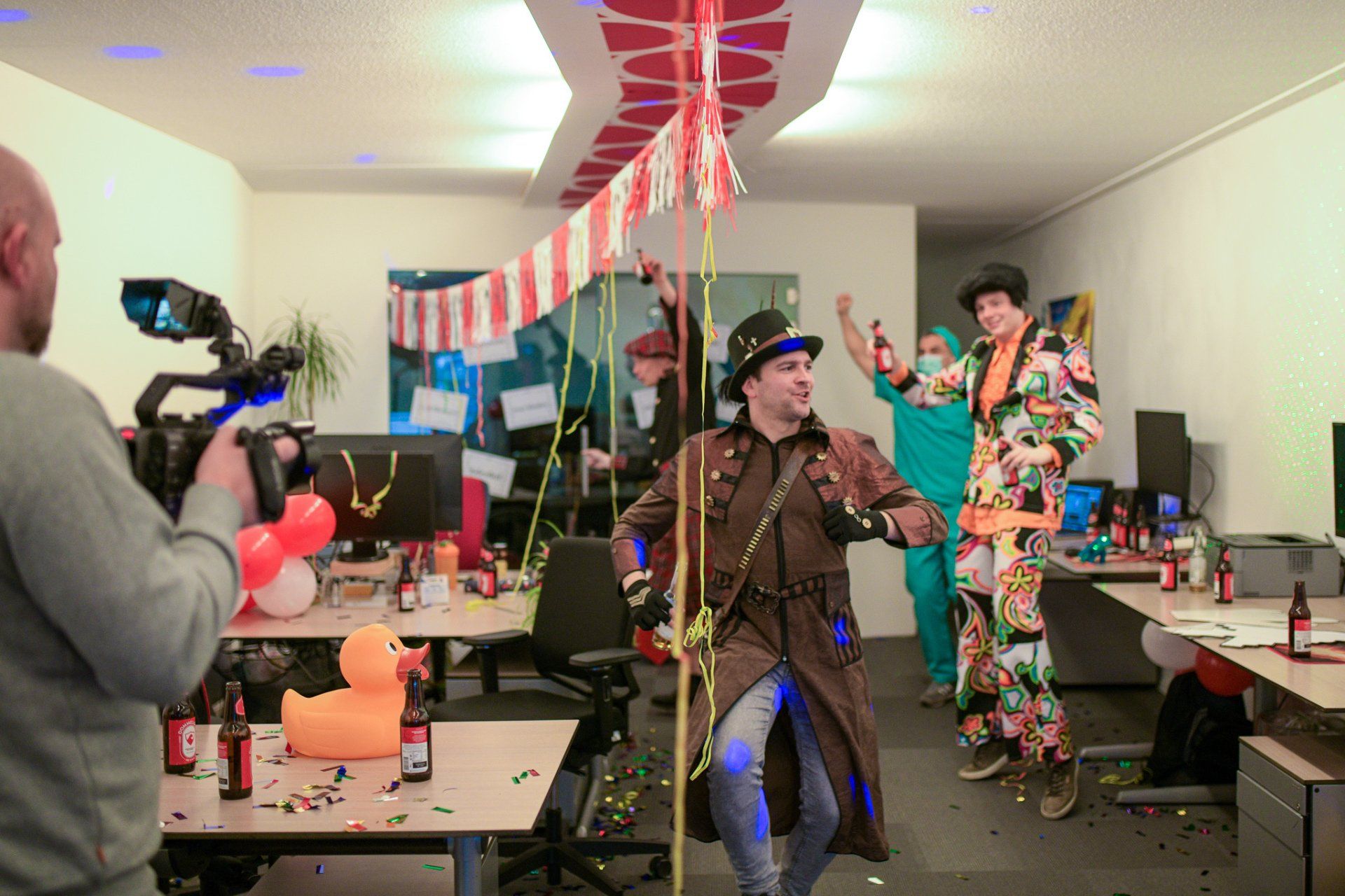 Een man maakt een foto van een groep dansende mensen in een kantoor.