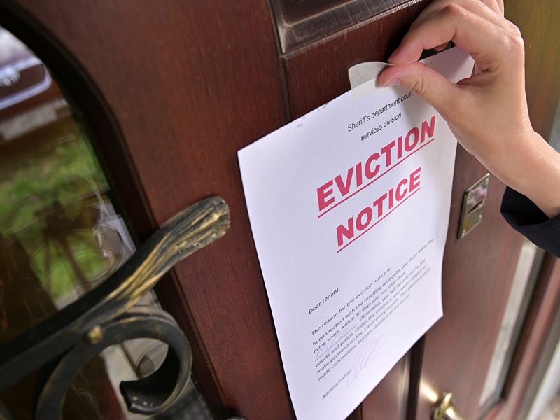 someone placing an eviction notice on a door